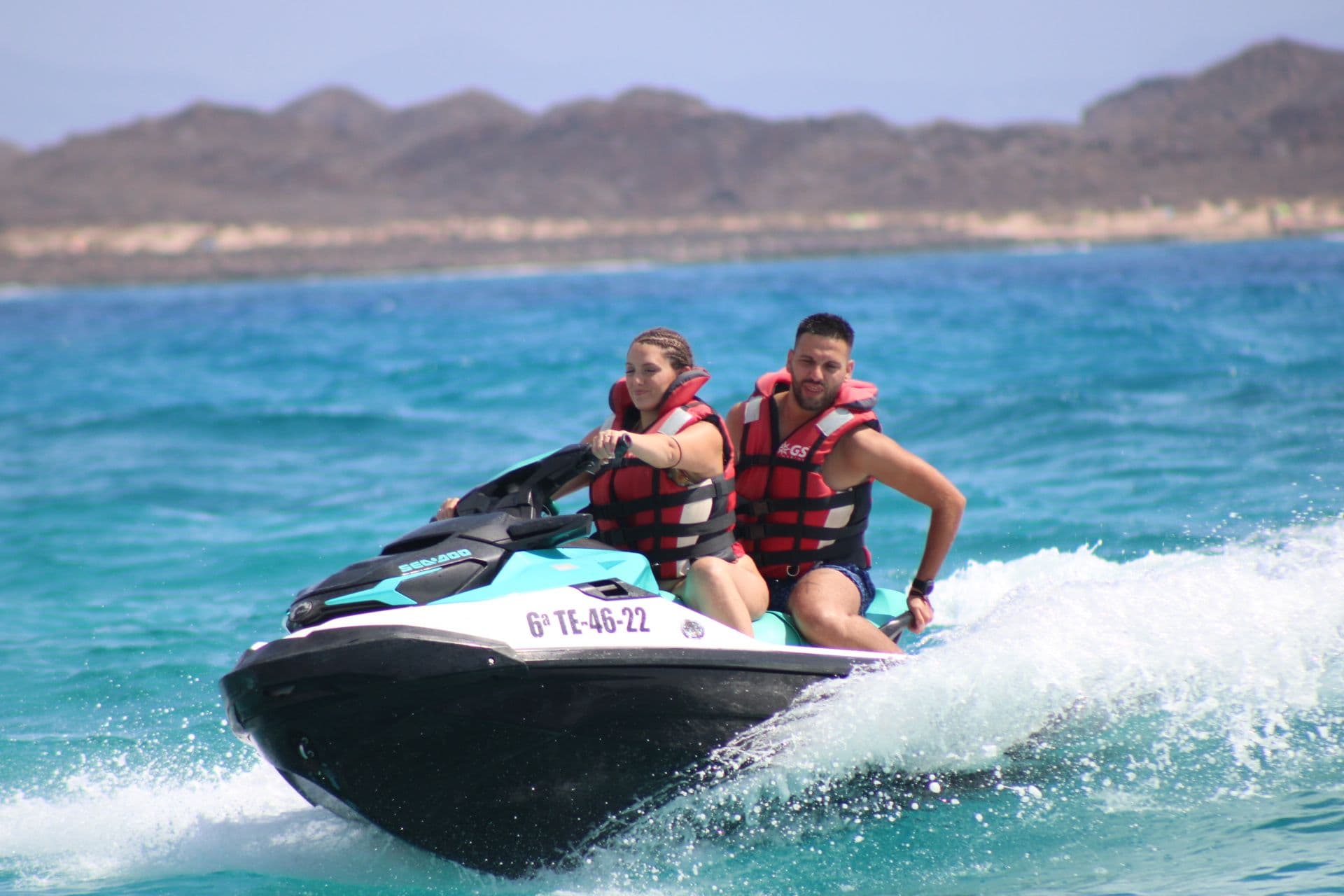 Couple on a turquoise Sea-Doo crossing the turquoise shallows between Fuerteventura and Isla de Lobos