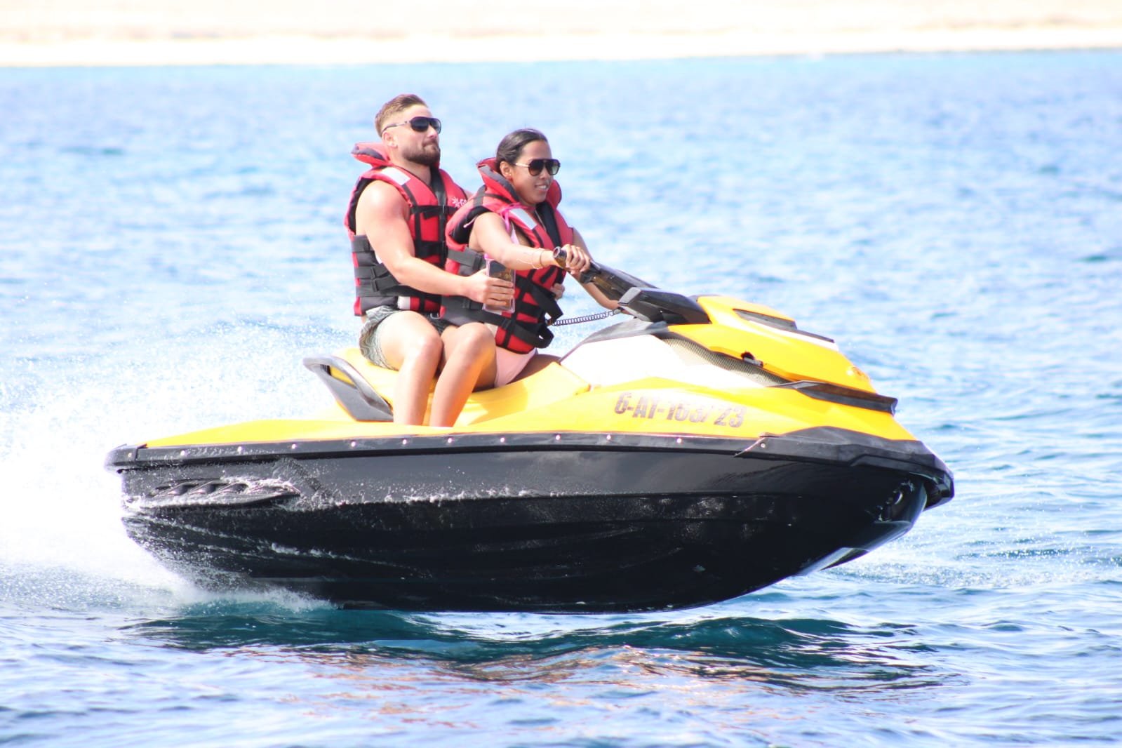 Couple wearing sunglasses cruising calmly on a yellow Sea-Doo jet ski near the Corralejo coast