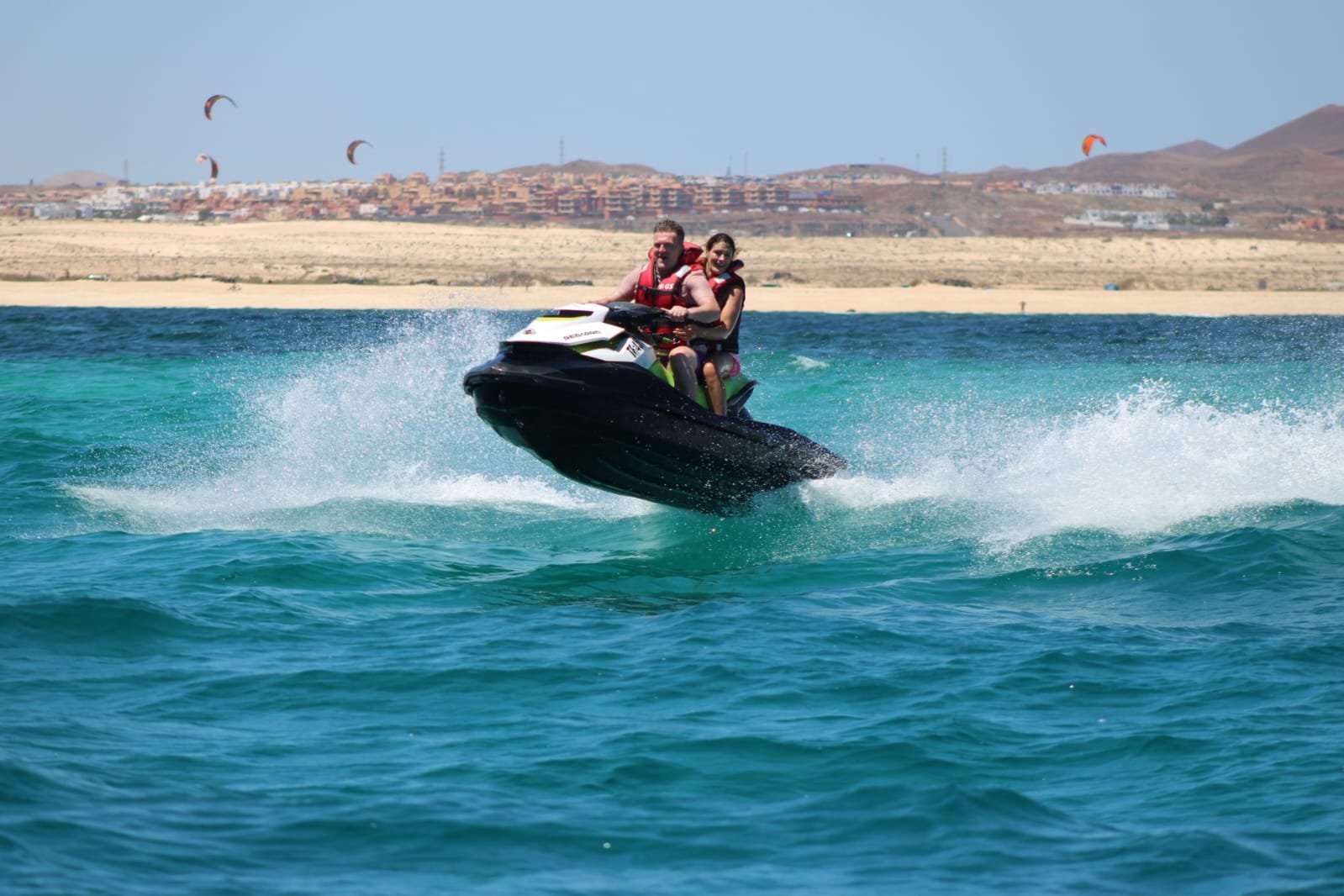 Solo male rider in sunglasses on a yellow jet ski cruising the turquoise water of Corralejo bay