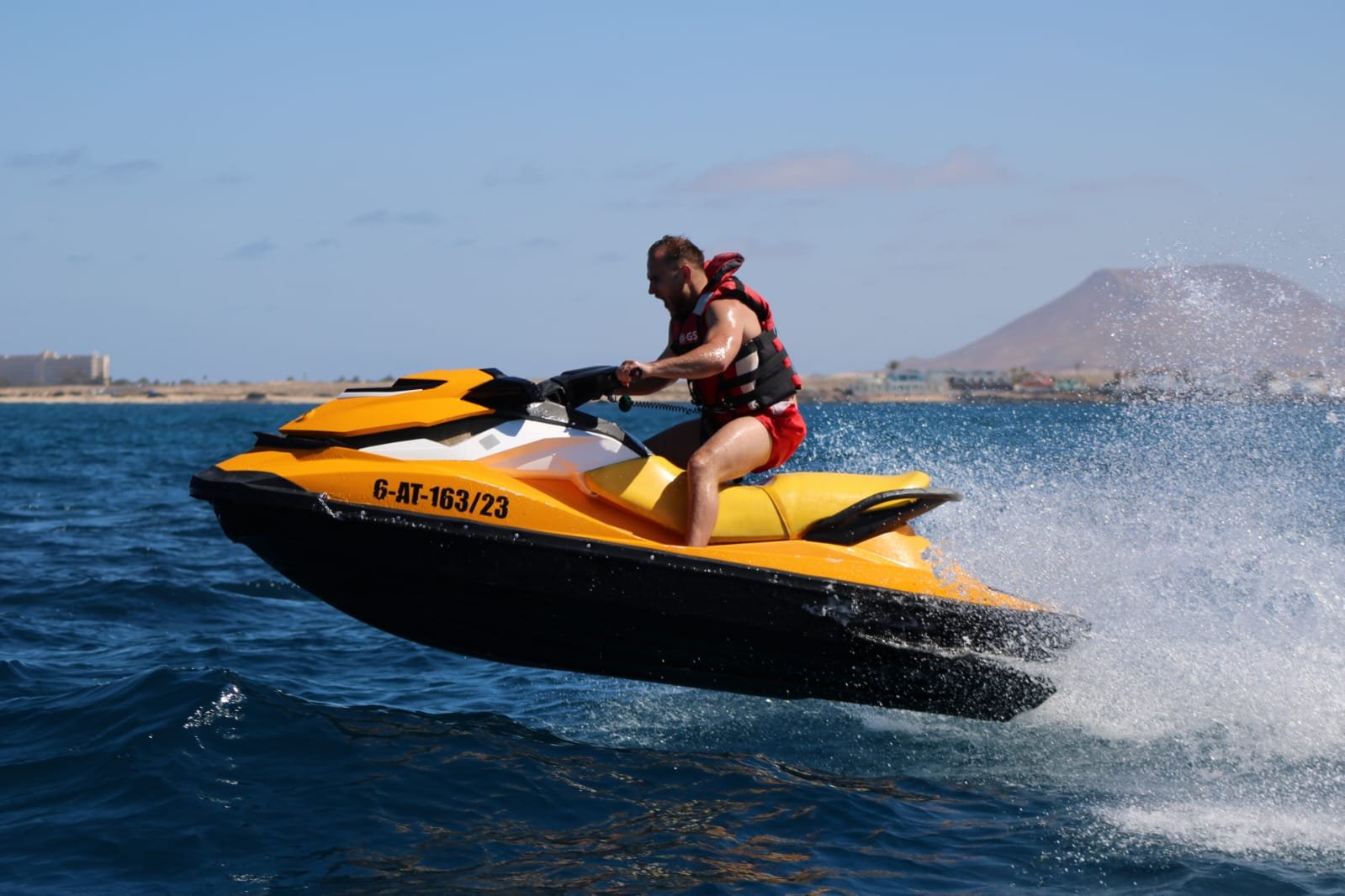 Yellow jet ski powering through wake spray on the deep blue Atlantic off Corralejo, Fuerteventura